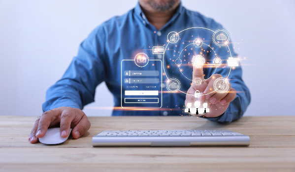 A man touches a digital screen in front of him while holding a mouse, next to a keyboard