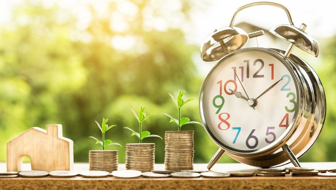 house made of wood, coins and a clock outside