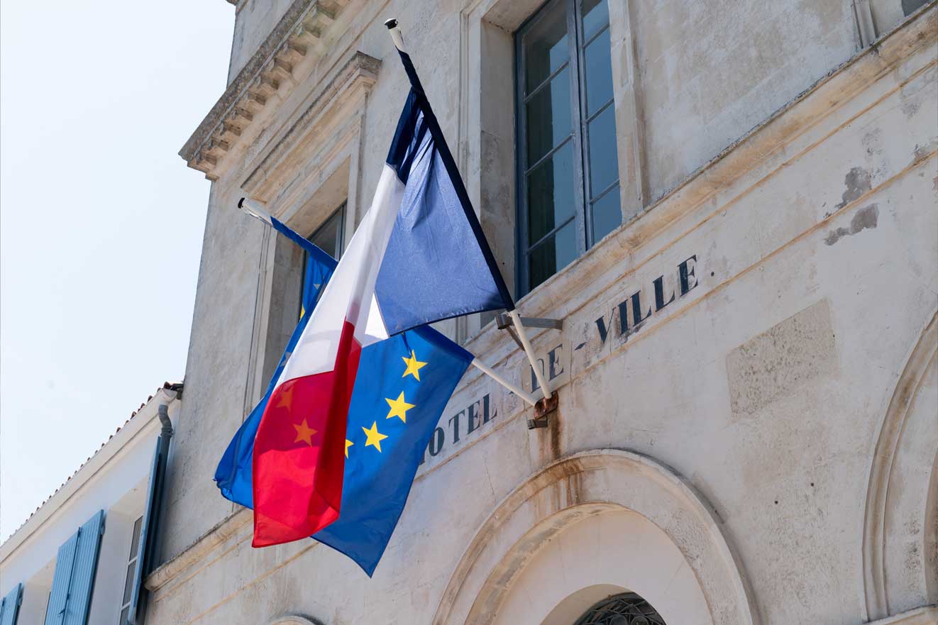 A French flag and a European flag hanging from the city hall's wall