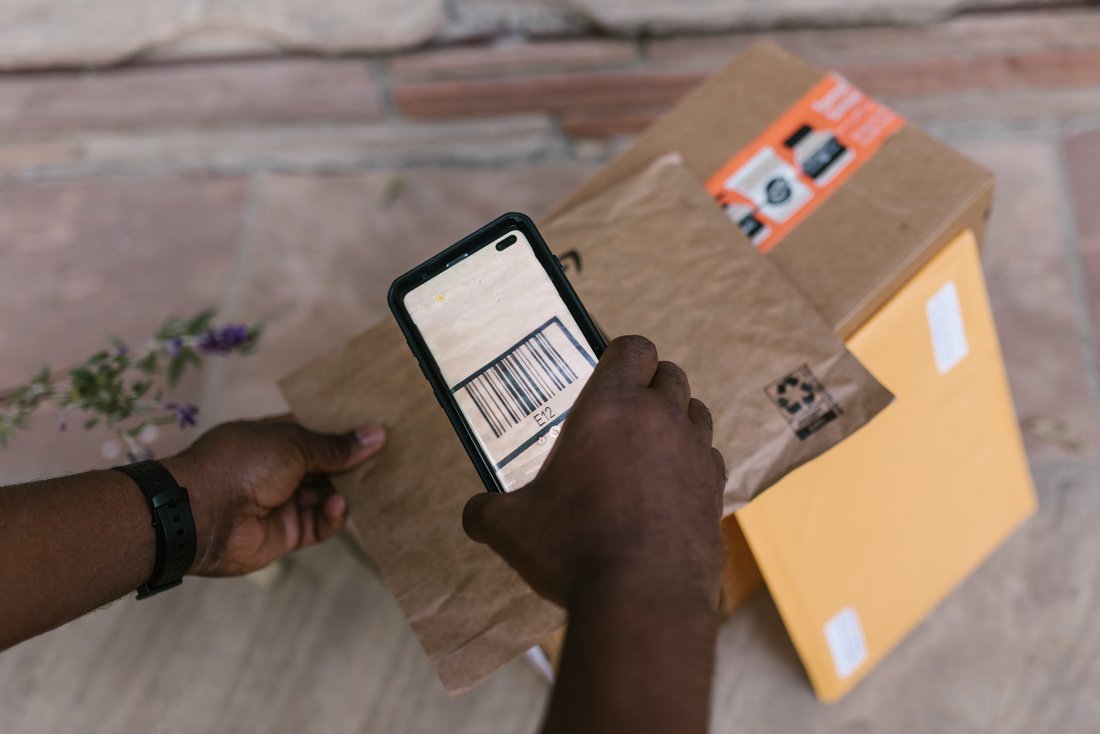 Close-up of hands scanning a parcel with a mobile phone.